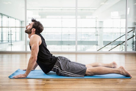 Handsome man on cobra pose on the mat